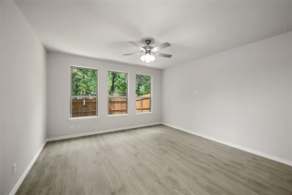 an empty room with windows and fan