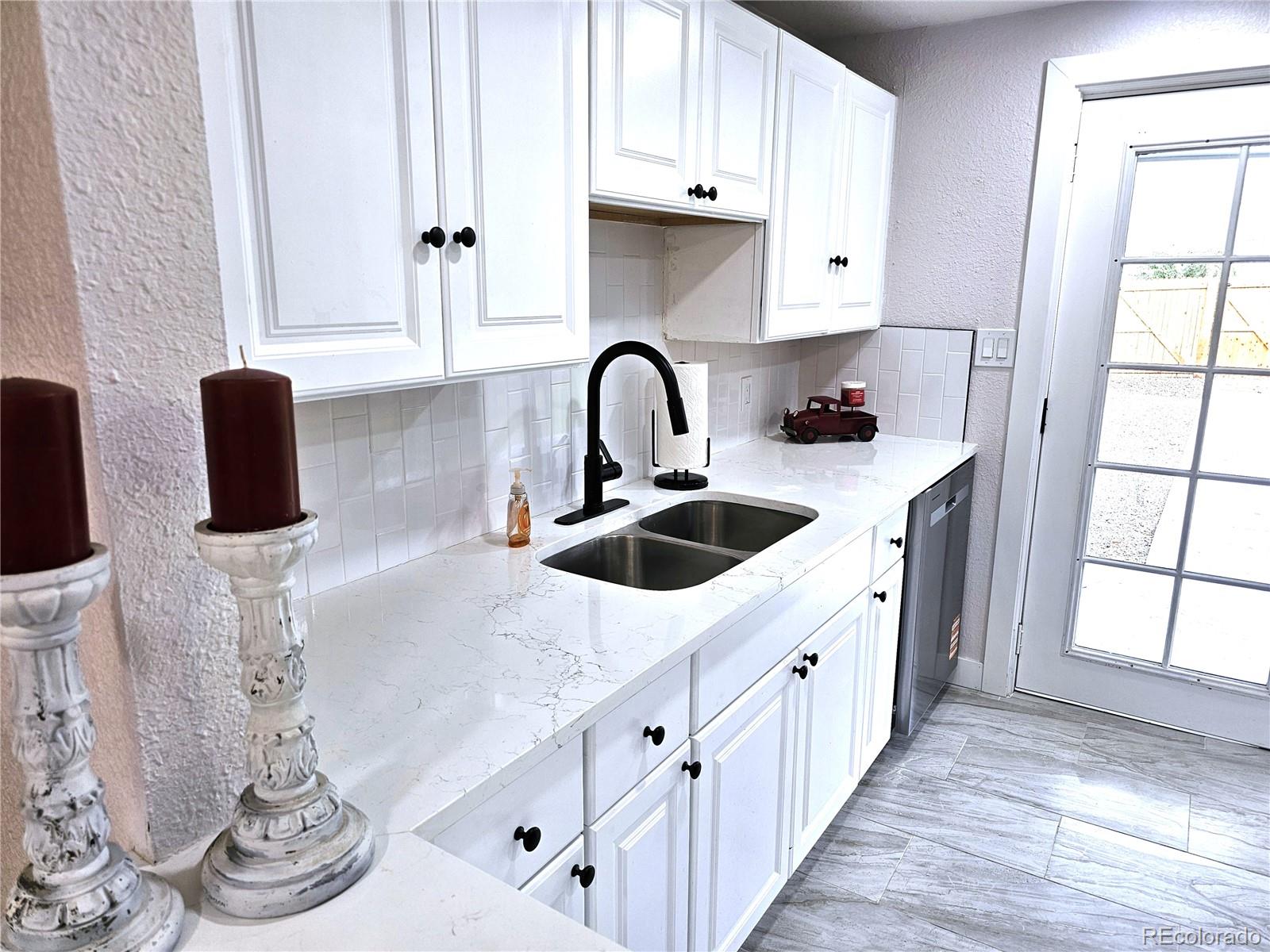 124 South Grove Street Denver, CO 80219 - Photo 6 of 25 a kitchen with white cabinets and window