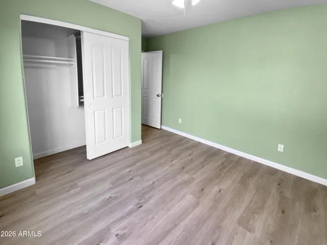 an empty room with wooden floor & closet area
