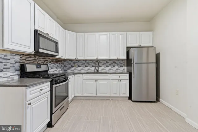 a kitchen with stainless steel appliances granite countertop a refrigerator stove a sink and a microwave