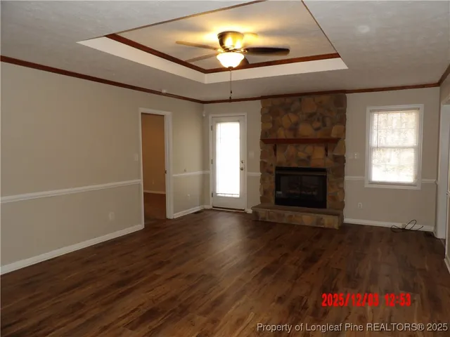 an empty room with wooden floor a fireplace and windows