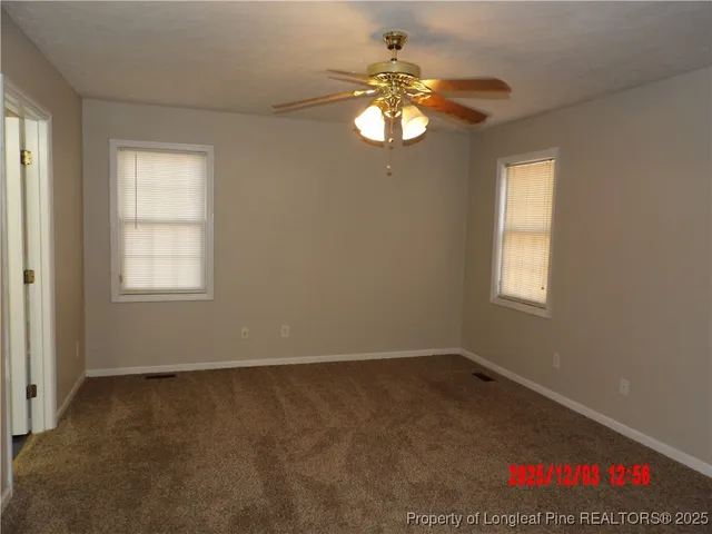 an empty room with a chandelier fan and windows