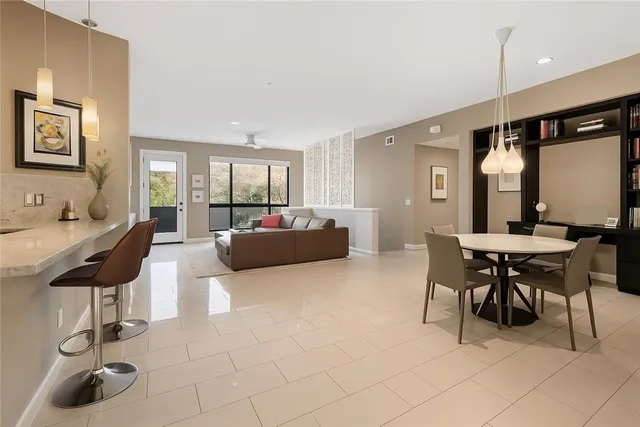 a living room with furniture and a dining table with projector the kitchen