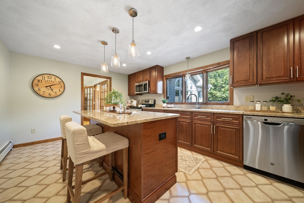 21 Cranberry Road Pepperell, MA 01463 - Photo 7 of 41 a kitchen with stainless steel appliances granite countertop a stove top oven a refrigerator a sink dishwasher with a dining table and chairs