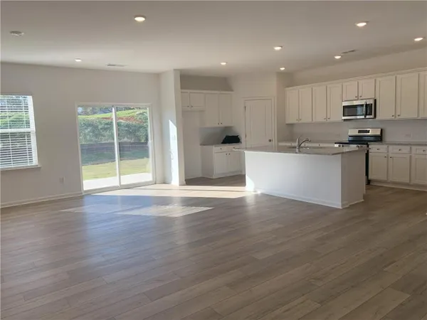 an open kitchen with white cabinets wooden floor and center island