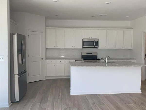 a kitchen with granite countertop a refrigerator and a stove top oven