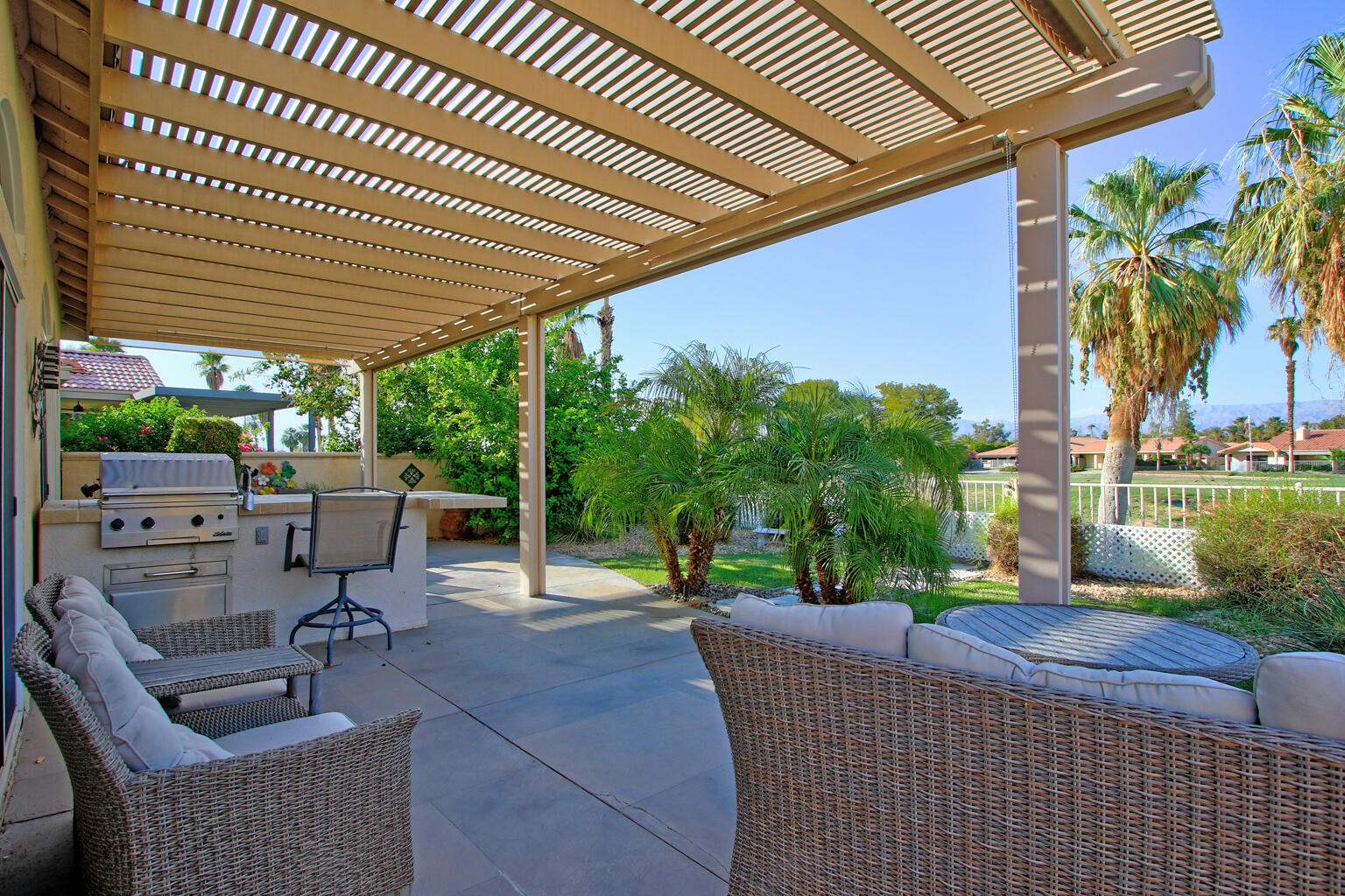 a view of a patio with couches and table and chairs with wooden fence and plants