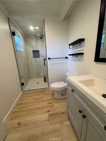 a bathroom with a sink a toilet a mirror and shower