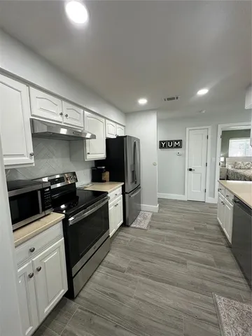 a kitchen with granite countertop a sink cabinets and stainless steel appliances