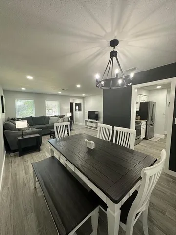 a view of a dining room and livingroom with furniture wooden floor a rug and a chandelier