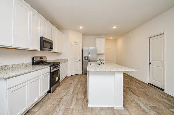 a kitchen with stainless steel appliances granite countertop a refrigerator a stove and a sink with wooden floors