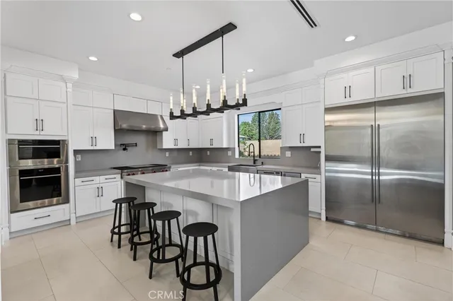 a kitchen with kitchen island a counter top space a sink stainless steel appliances and cabinets