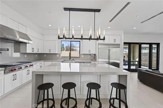 a kitchen with stainless steel appliances granite countertop a stove a sink and white cabinets with wooden floor