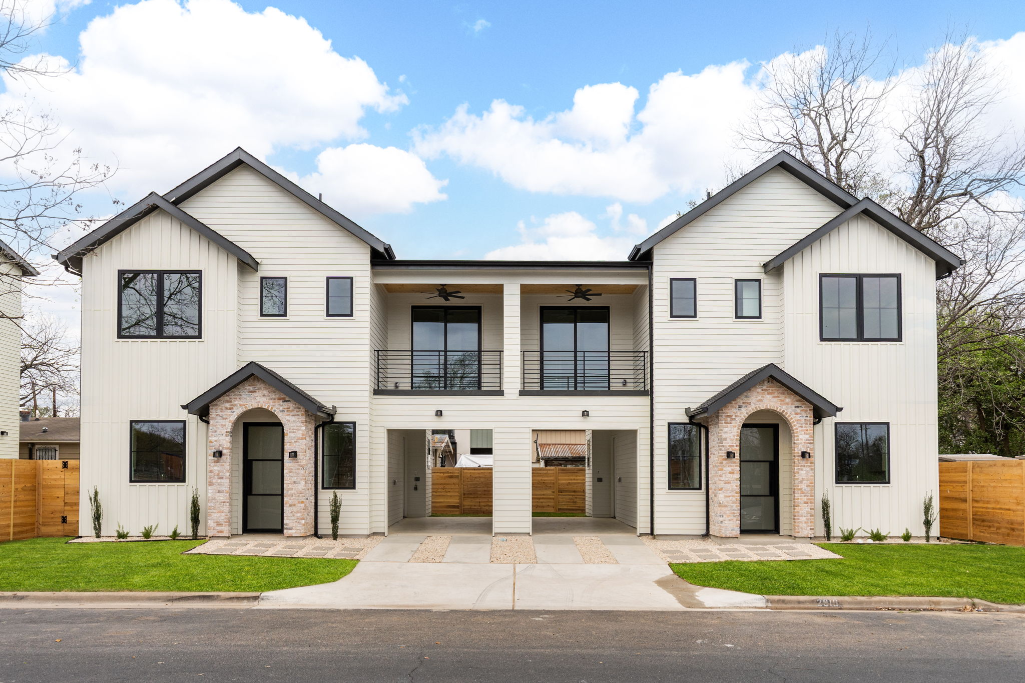 View of front of property featuring a balcony, ceiling fan, and brick siding