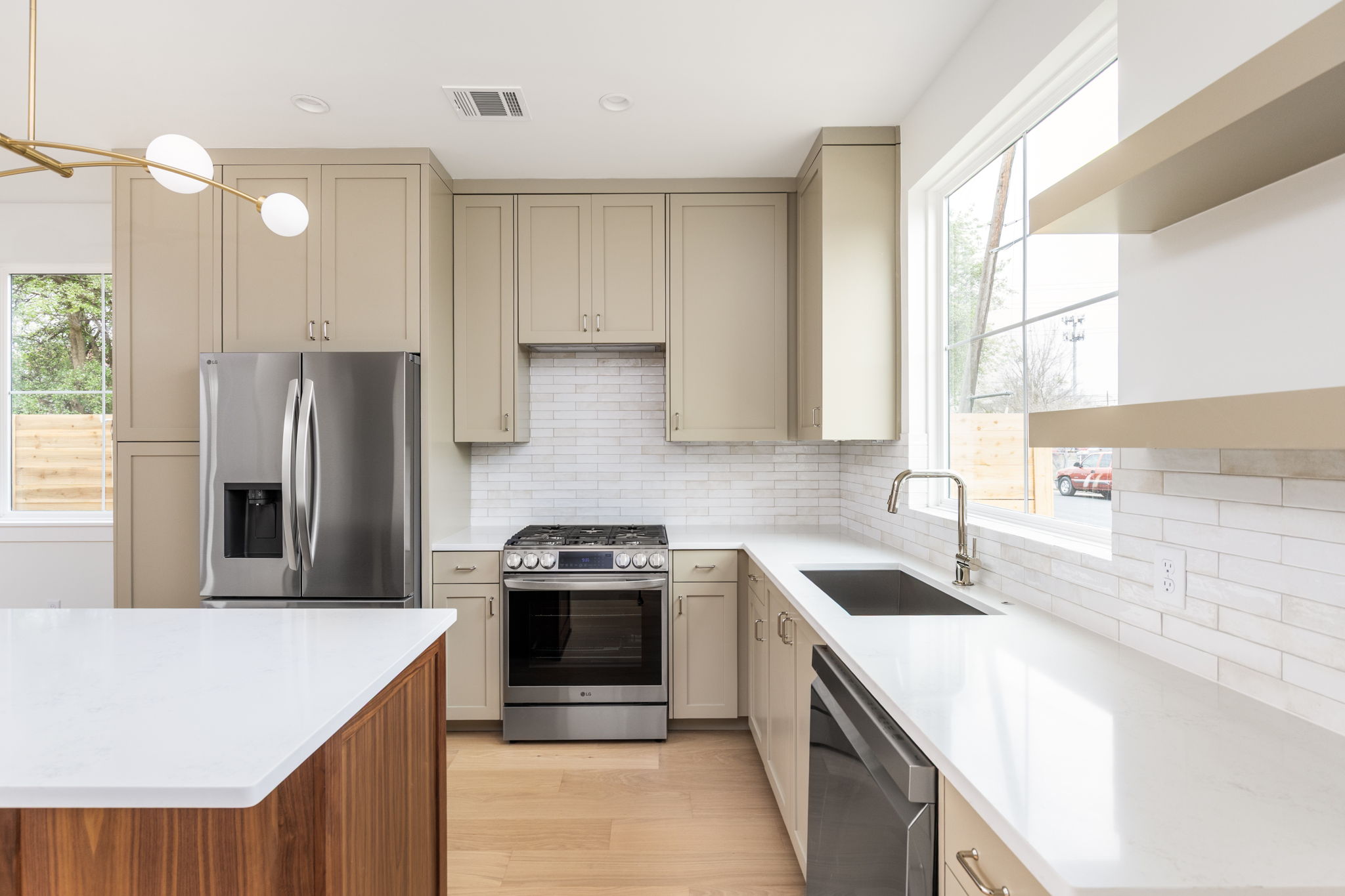 408 Linden Street, Unit B Austin, TX 78702 - Photo 11 of 40 Kitchen featuring stainless steel appliances, cream cabinetry, decorative backsplash, light stone countertops, and light wood-style flooring