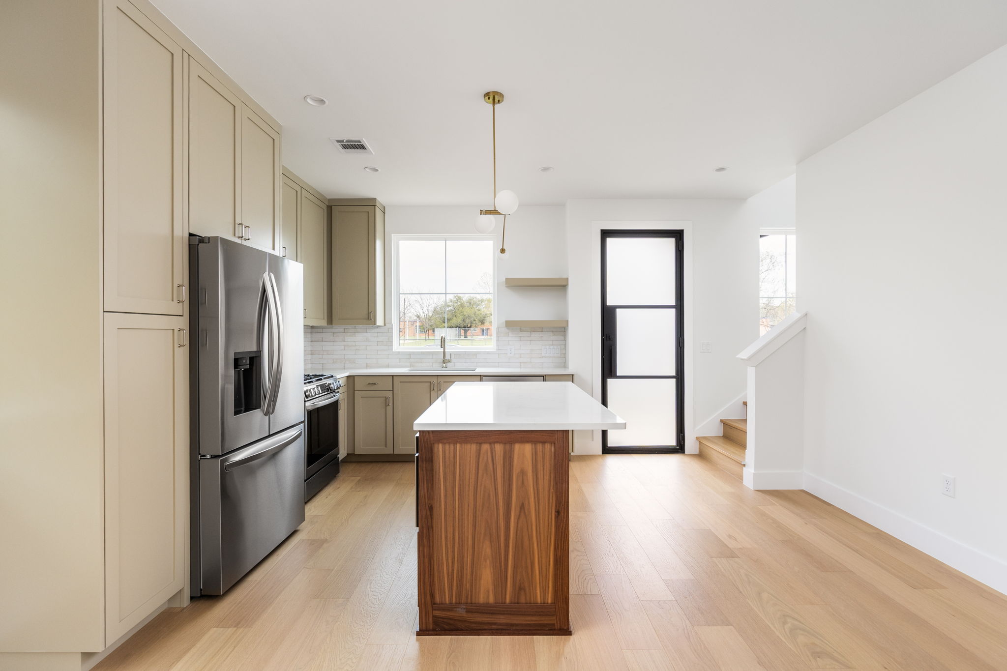 408 Linden Street, Unit B Austin, TX 78702 - Photo 13 of 40 Kitchen featuring stainless steel appliances, a center island, light wood-type flooring, open shelves, and backsplash