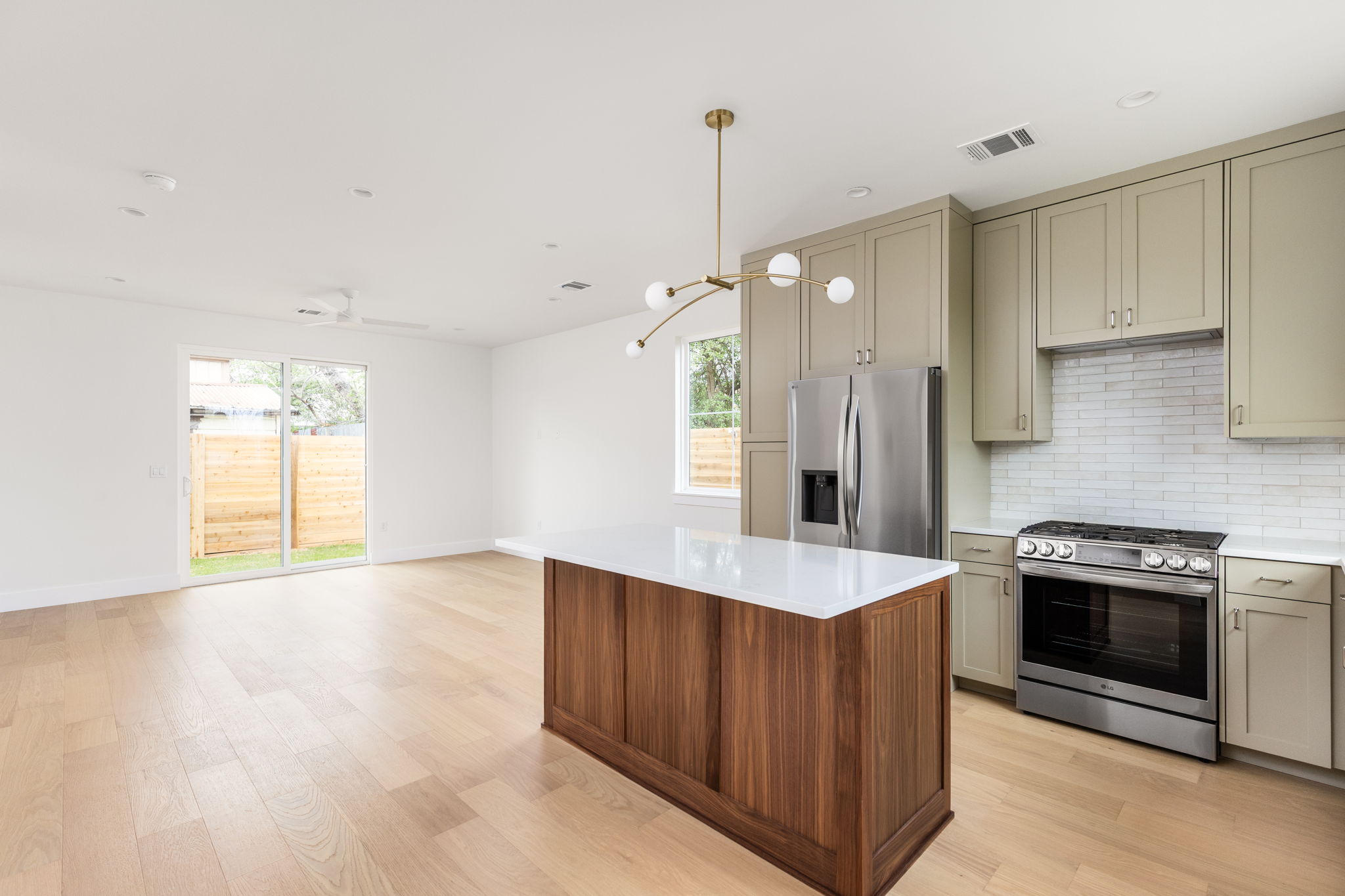 408 Linden Street, Unit B Austin, TX 78702 - Photo 39 of 40 Kitchen featuring stainless steel appliances, light wood-type flooring, decorative backsplash, hanging light fixtures, and open floor plan