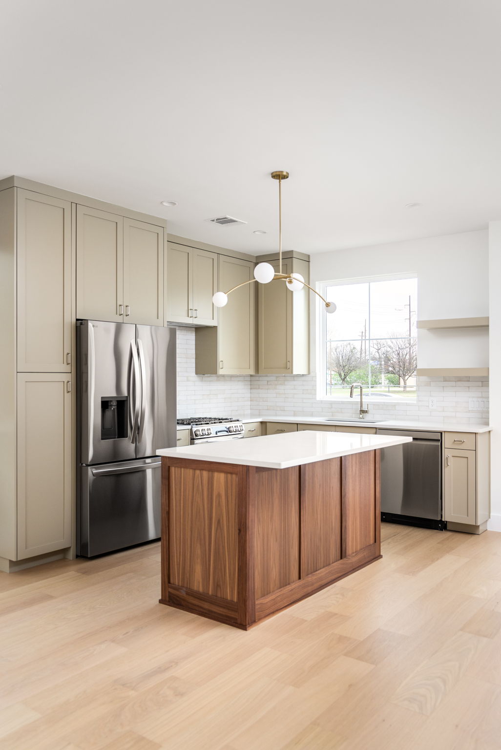 408 Linden Street, Unit B Austin, TX 78702 - Photo 8 of 40 Kitchen featuring stainless steel appliances, light wood-style floors, a center island, decorative light fixtures, and backsplash