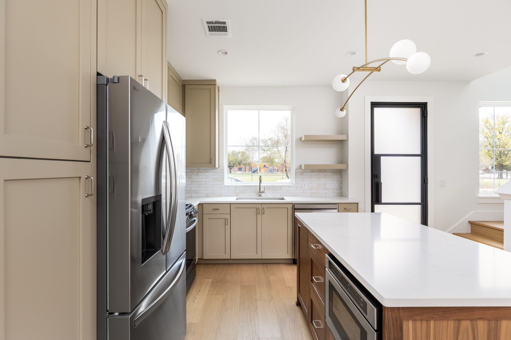 408 Linden Street, Unit B Austin, TX 78702 - Photo 9 of 40 Kitchen featuring stainless steel appliances, a kitchen island, light wood-type flooring, open shelves, and cream cabinets