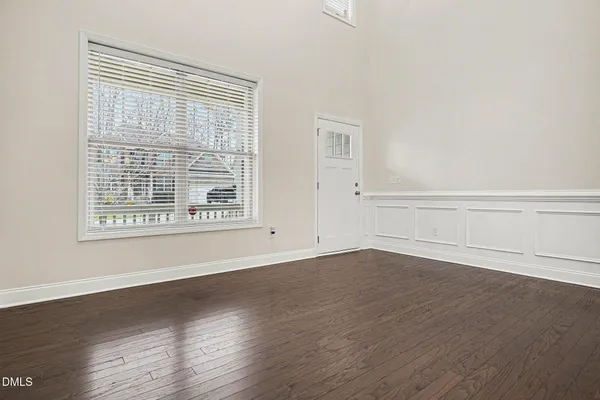 an empty room with wooden floor chandelier and windows