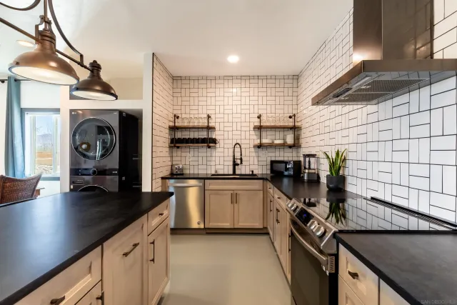 a kitchen with stainless steel appliances granite countertop a sink a stove a refrigerator cabinets and chairs