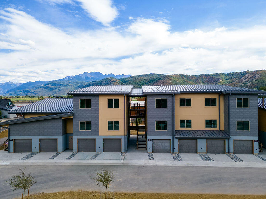 176 Alpine Lane, Unit 300 M2 301 Ridgway, CO 81432 - Photo 19 of 37 a view of a white house with large windows and a small yard