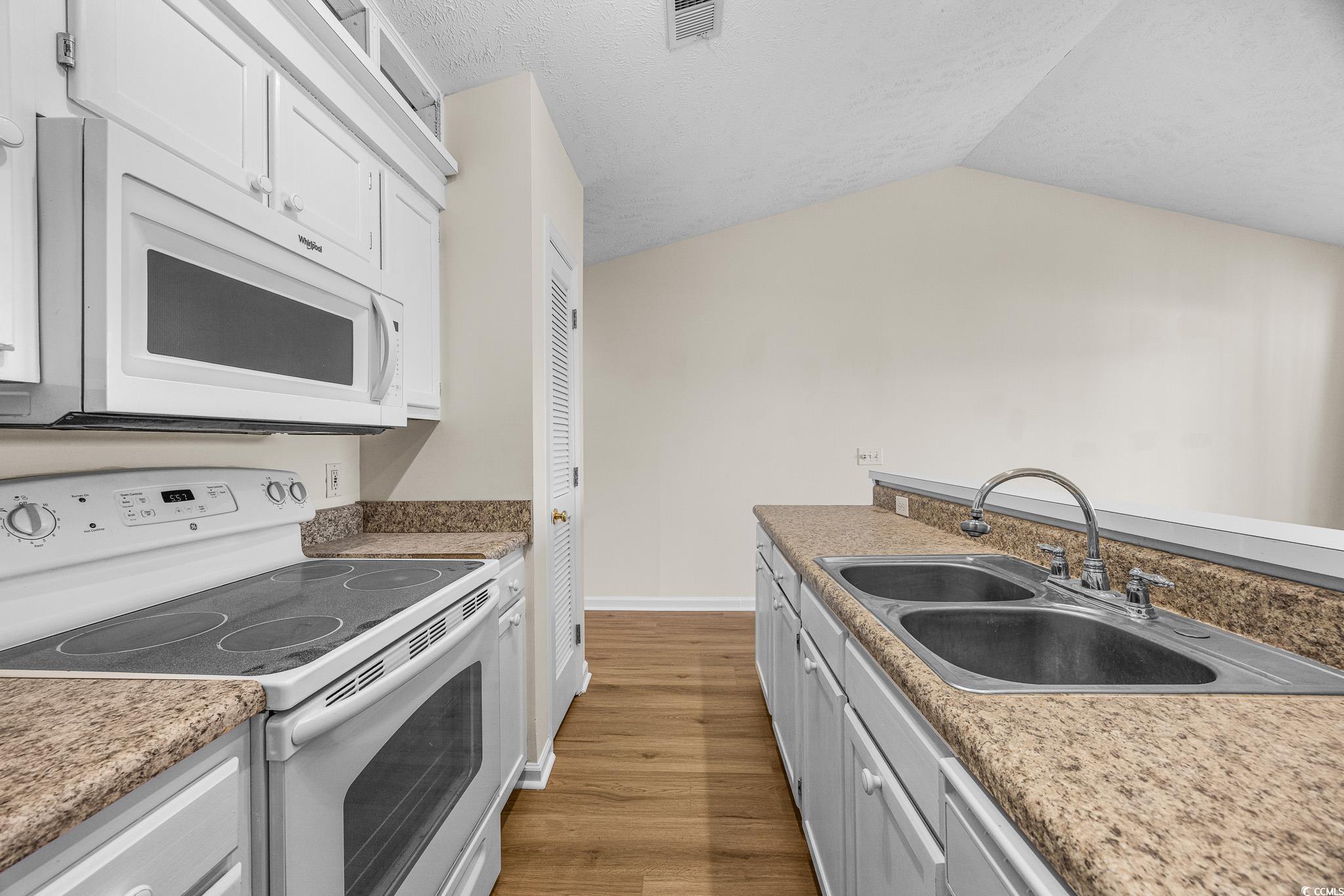 673 Tupelo Lane, Unit 19H Longs, SC 29568 - Photo 8 of 22 Kitchen featuring white appliances, white cabinets, light wood-style floors, and a textured ceiling