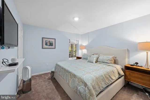 a bedroom with a bed a lamp and a flat screen tv