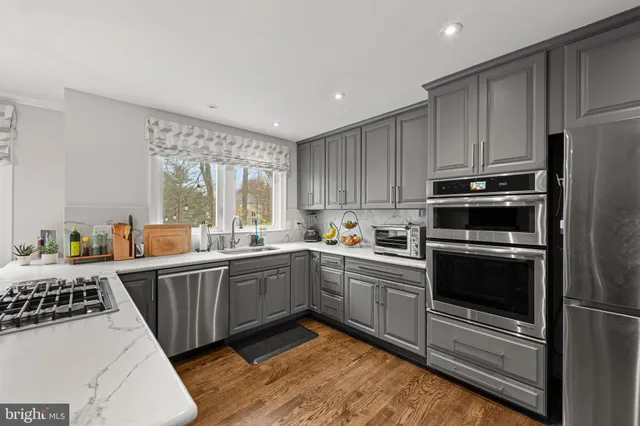 a kitchen with granite countertop a sink stainless steel appliances and cabinets