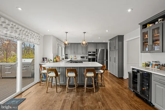 a kitchen with stainless steel appliances a dining table chairs and wooden floor