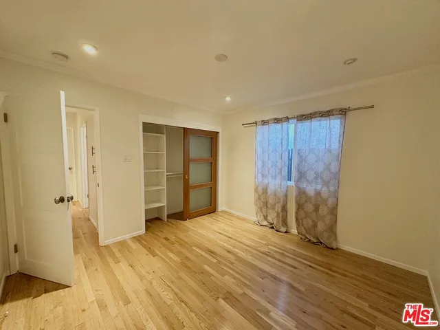 a view of an empty room with wooden floor and closet