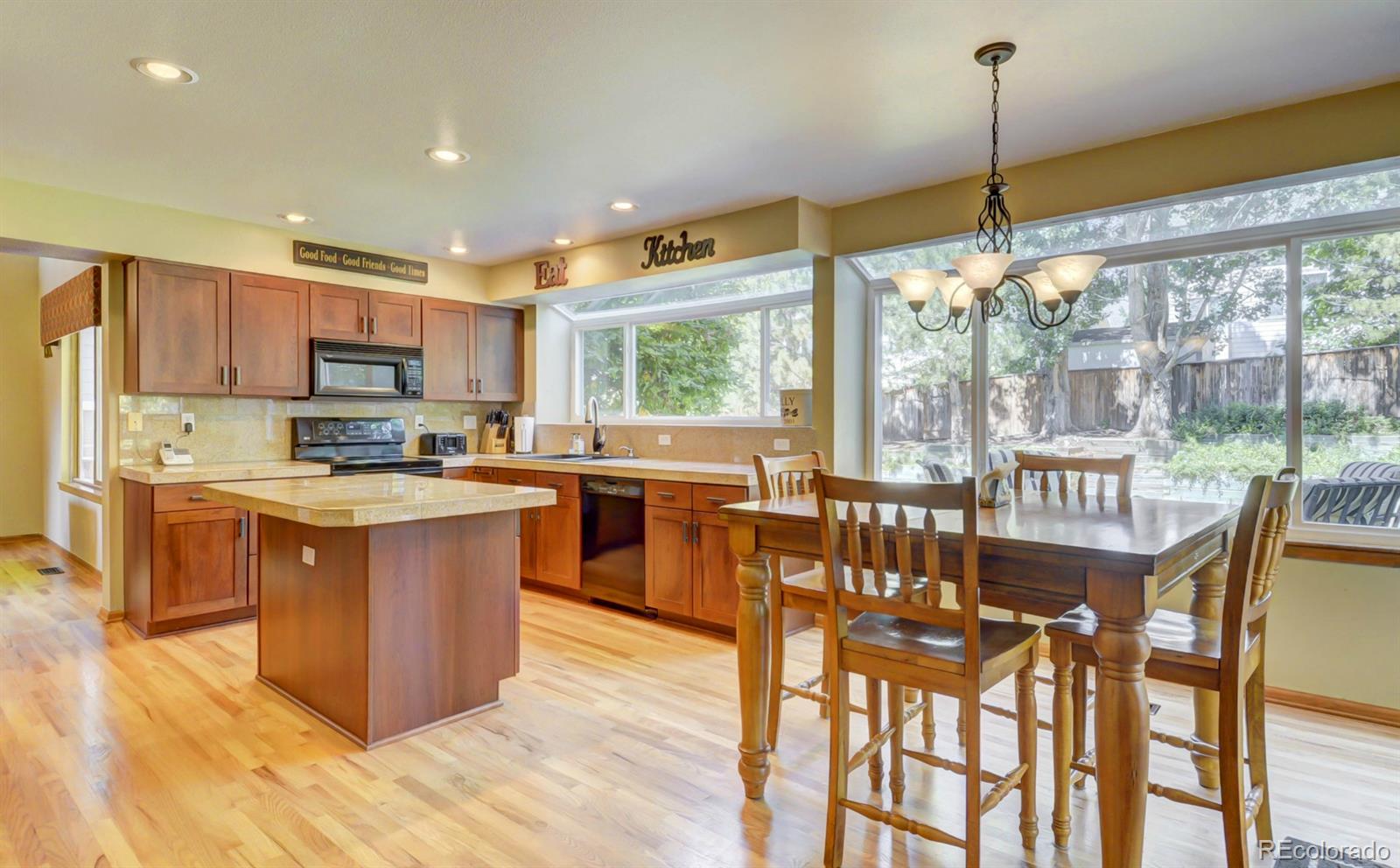 9932 South Spring Hill Place Highlands Ranch, CO 80129 - Photo 11 of 31 a kitchen with stainless steel appliances granite countertop a stove top oven a sink dishwasher a dining table and chairs with wooden floor