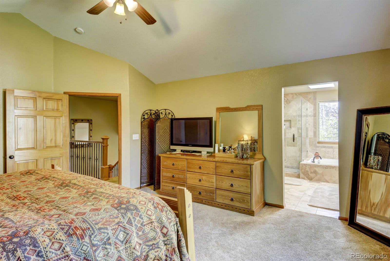 9932 South Spring Hill Place Highlands Ranch, CO 80129 - Photo 15 of 31 a large bedroom with a bed and flat screen tv