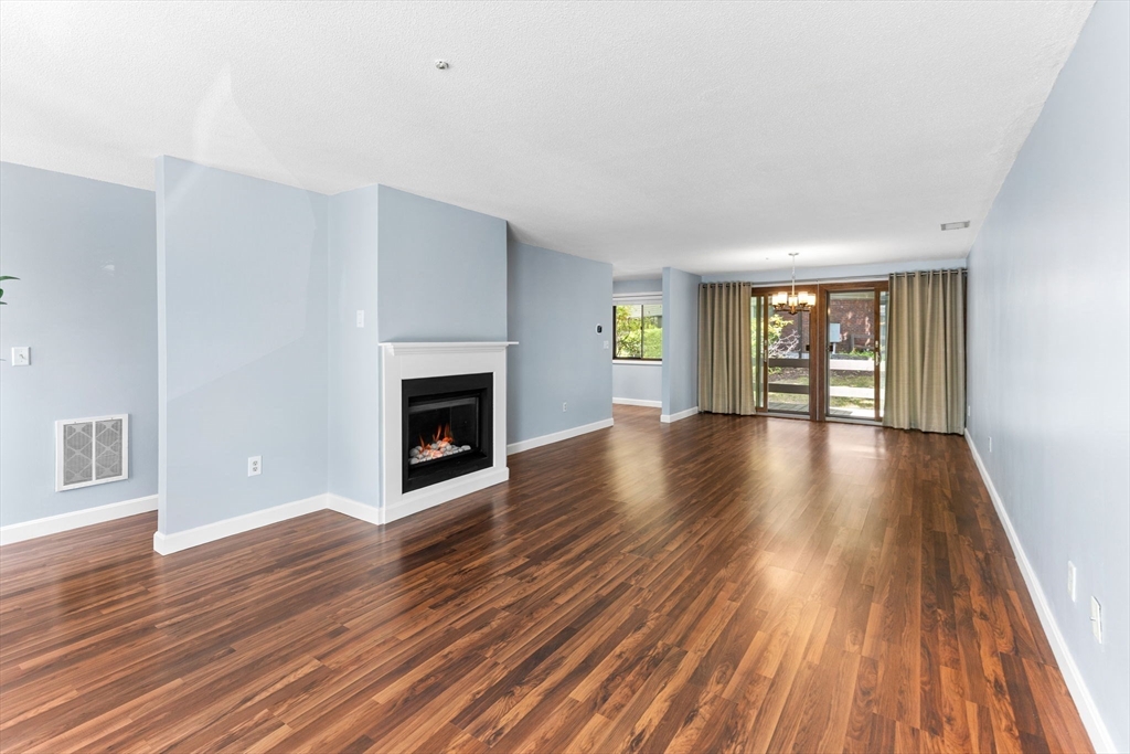 511 Tumbling Hawk, Unit 511 Acton, MA 01718 - Photo 13 of 42 an empty room with wooden floor and fireplace