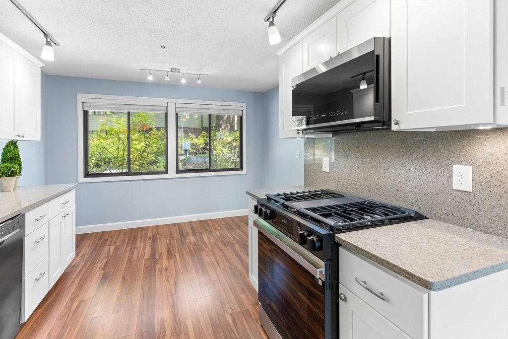 511 Tumbling Hawk, Unit 511 Acton, MA 01718 - Photo 15 of 42 a kitchen with granite countertop a stove and a wooden floor