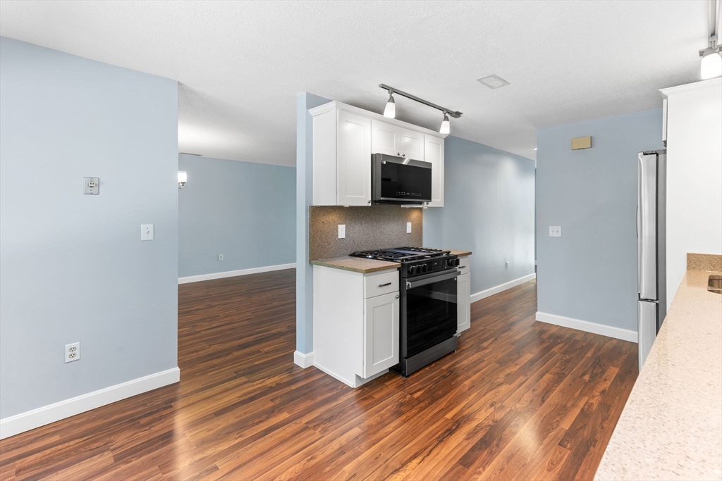 511 Tumbling Hawk, Unit 511 Acton, MA 01718 - Photo 16 of 42 a kitchen with granite countertop a stove and a wooden floor