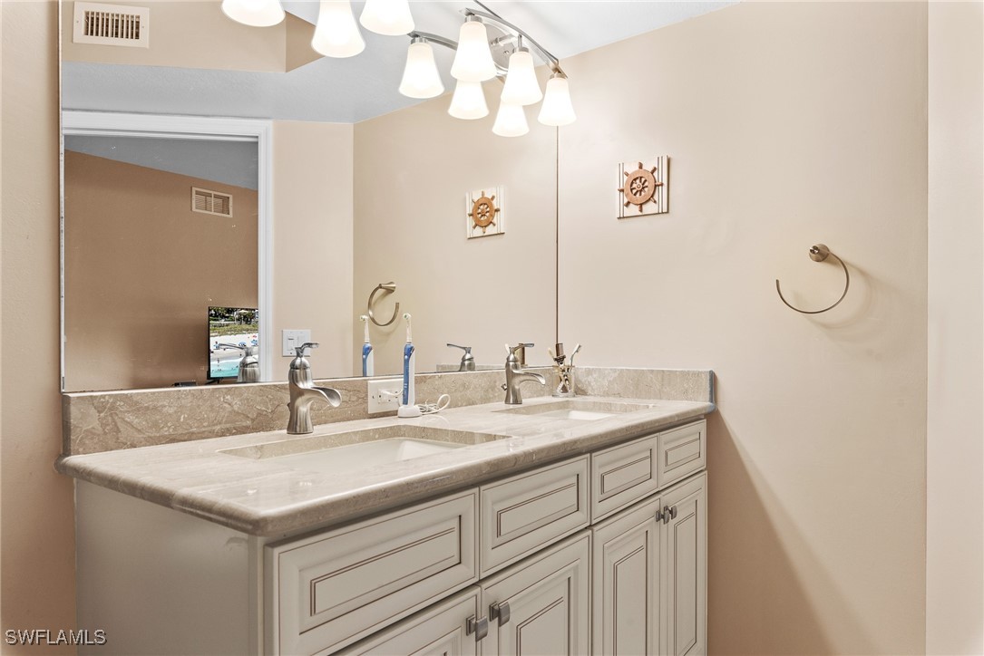 4965 Sandra Bay Drive, Unit 103 Naples, FL 34109 - Photo 14 of 30 a bathroom with a granite countertop sink and a mirror