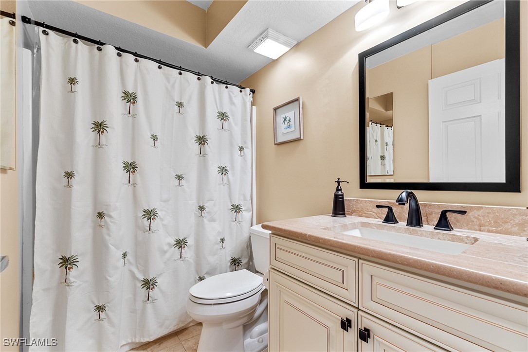 4965 Sandra Bay Drive, Unit 103 Naples, FL 34109 - Photo 18 of 30 a bathroom with a toilet a sink and a mirror