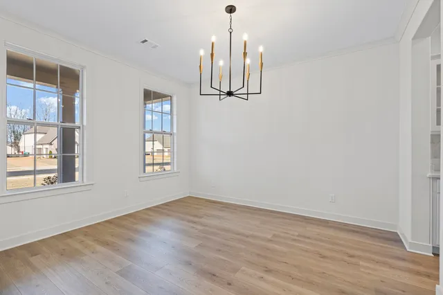 a view of an empty room with wooden floor and windows