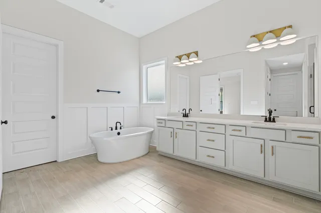 a bathroom with a sink vanity tub and mirror