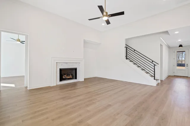 a view of an empty room with wooden floor fireplace and a window