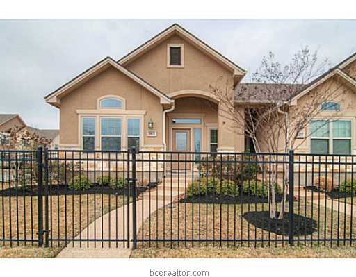 a view of a white house with a small yard and wooden fence