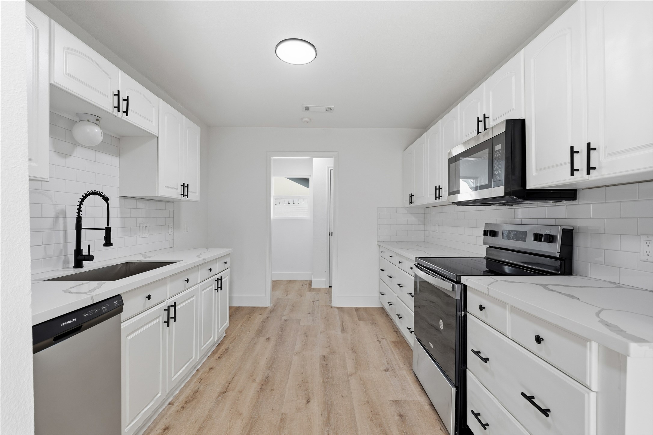 9809 Wren Court Conroe, TX 77385 - Photo 9 of 22 a kitchen with stainless steel appliances granite countertop a stove top oven a sink dishwasher and white cabinets with wooden floor
