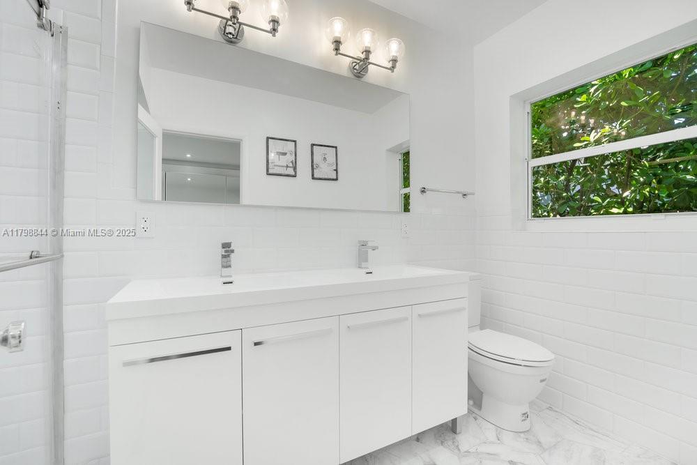 9025 Hawthorne Avenue Surfside, FL 33154 - Photo 24 of 58 a bathroom with a toilet a sink a mirror and a window