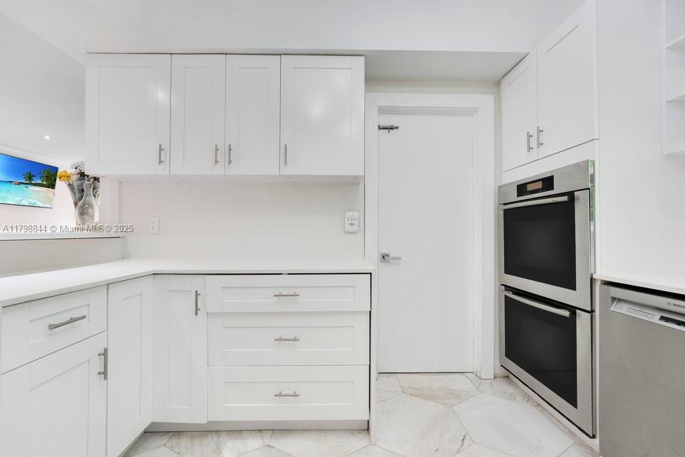 9025 Hawthorne Avenue Surfside, FL 33154 - Photo 27 of 58 a kitchen with white cabinets and stainless steel appliances