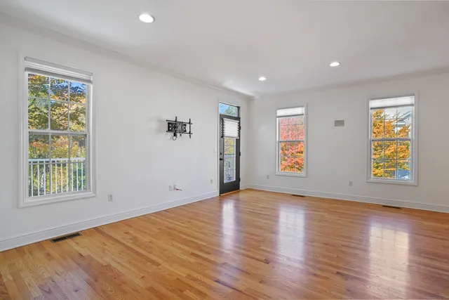 a view of an empty room with window and wooden floor