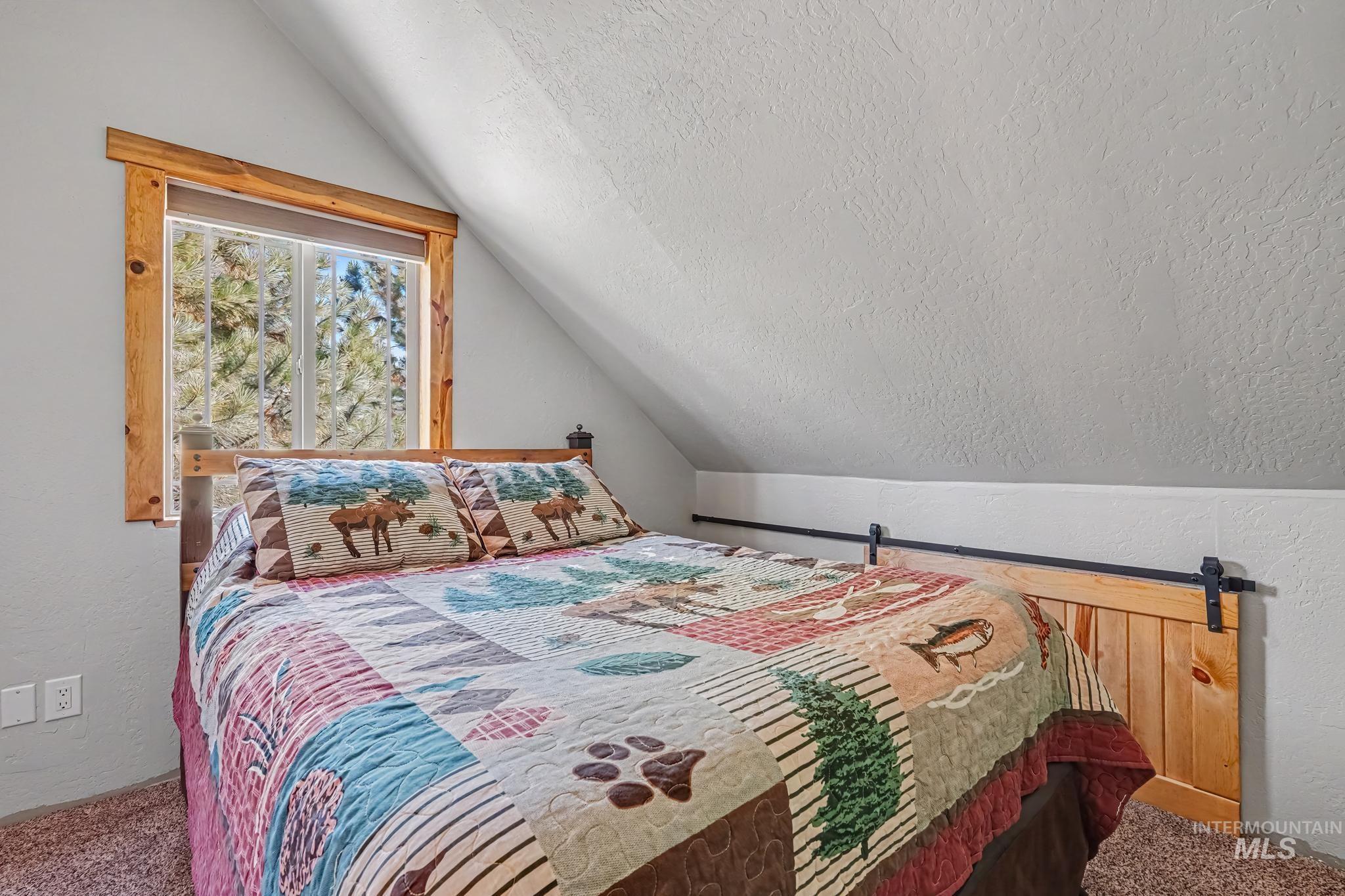 106 Wilderness Lake Road Cascade, ID 83611 - Photo 10 of 35 Sloped ceiling room featuring a window with natural wood trim and a panel accent wall