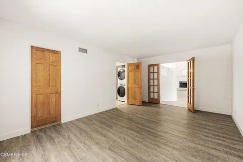 a view of an empty room with window and wooden floor