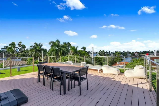 a view of a roof deck with table and chairs couches with wooden floor and fence