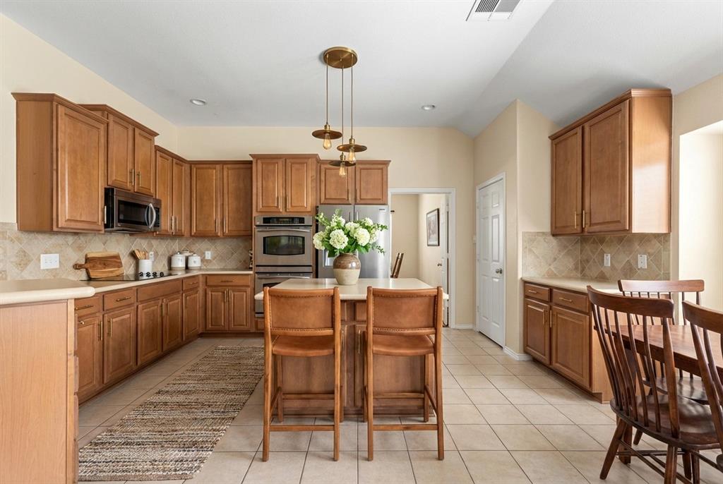 12334 Blue Ridge Drive Frisco, TX 75033 - Photo 9 of 20 a kitchen with stainless steel appliances granite countertop a stove top oven a refrigerator a sink dishwasher a dining table and chairs with wooden floor